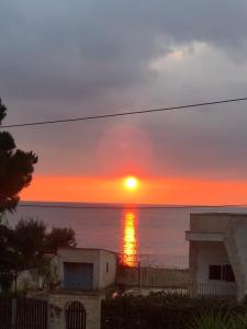 un tramonto su un corpo d'acqua con un edificio di La Conchiglia a Taranto