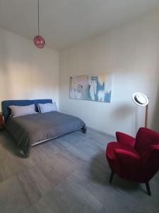 - une chambre avec un lit et une chaise rouge dans l'établissement L'Appartamento Storico dal Design Moderno, à Faenza