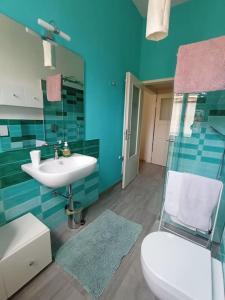 La salle de bains bleue est pourvue de toilettes et d'un lavabo. dans l'établissement L'Appartamento Storico dal Design Moderno, à Faenza