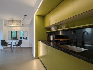 een keuken met groene en zwarte kasten en een tafel bij Casa Ambar Apartments in Panama-Stad