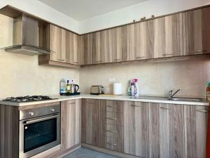 a kitchen with wooden cabinets and a stove top oven at MIVE-Delux Three Bedroom Apartment in Marsaskala in Marsaskala