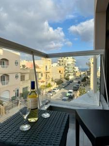Una botella de vino y dos copas en una mesa en un balcón. en MIVE-Delux Three Bedroom Apartment in Marsaskala, en Marsaskala