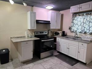 a kitchen with white cabinets and a black stove top oven at Comforting getaway-sleeps 6-walk to falls! in Niagara Falls