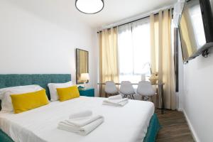 1 dormitorio con 1 cama blanca grande con almohadas amarillas en Vibrant Studio Close To Panepistimio Metro-Zaloggou str, en Atenas
