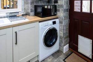 a kitchen with a washing machine and a microwave at Heritage Cottage by StayStaycations in Pontypridd