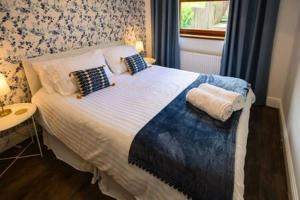 um quarto com uma cama com almofadas e uma janela em Heritage Cottage by StayStaycations em Pontypridd