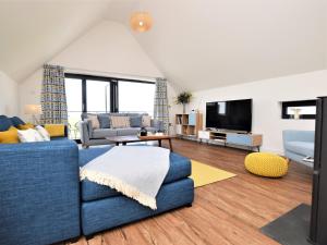 ein Wohnzimmer mit einem blauen Sofa und einem TV in der Unterkunft 4 Bed in Westward Ho 75358 in Northam