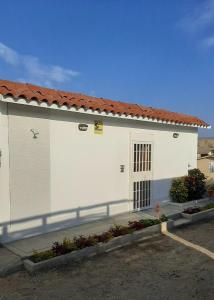 um edifício branco com um telhado vermelho em La Silvita - Casa de playa em Los Órganos