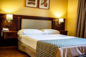 a hotel room with a large bed and two lamps at Hotel Spa Tudanca Aranda in Aranda de Duero