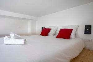 Una cama blanca con dos almohadas rojas. en Modern Loft in Paris Montreuil, en Montreuil