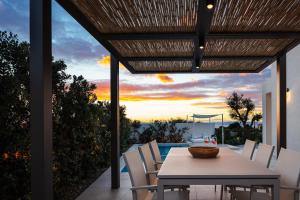 a dining table and chairs on a patio with a sunset at Villa Venetiko in Chania