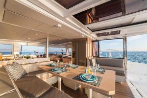 a dining room on a yacht with a table and chairs at Catamarano 43 Foil e Kite Equipment in Marina di Portisco