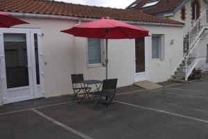 un patio con mesa, sillas y sombrilla roja en Studio 2 personnes proche plage parking gratuit : 27, en La Bernerie-en-Retz