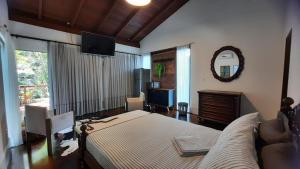 a bedroom with a bed and a couch and a mirror at Casa da Mata in Itapema
