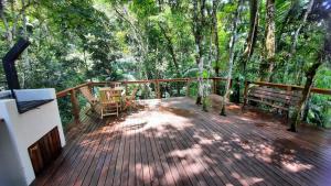 eine Holzterrasse mit einem Tisch und Bänken darauf in der Unterkunft Casa da Mata in Itapema