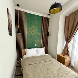 - une chambre avec un lit et un mur vert dans l'établissement House4You - Bălcescu 26, à Bucarest