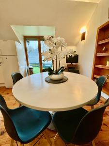 un tavolo da pranzo con sedie e un vaso con fiori di GITE DANINOU; meublé 3 chambres avec terrasse (1er étage du château) , salon et cuisine ouverte a Vouvray