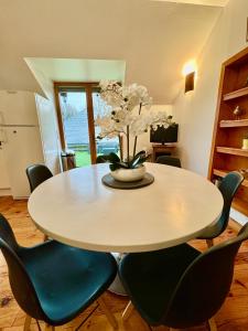 a dining room table with chairs and a vase with flowers at GITE DANINOU; meublé 3 chambres avec terrasse (1er étage du château) , salon et cuisine ouverte in Vouvray