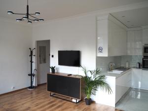 a white kitchen with a flat screen tv on the wall at Grand-Tourist Old Town Center Apartments in Gdańsk