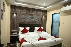 a bedroom with a large bed with red pillows at Hotel Trax International in Jamshedpur