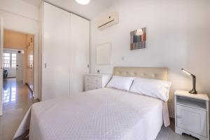 a white bedroom with a white bed and a lamp at Pageant Homes in Nicosia