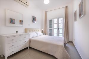 um quarto branco com uma cama branca e uma janela em Pageant Homes em Nicósia