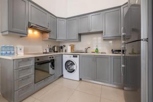 eine Küche mit grauen Schränken, einer Waschmaschine und einem Trockner in der Unterkunft Pageant Homes in Nikosia
