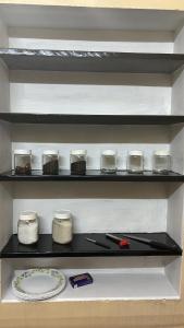 a shelf in a kitchen with jars and a plate at Kokaris Coorg Homestay in Kushālnagar