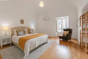 a white bedroom with a bed and a chair at Home near Évora's main square with private terrace in Évora