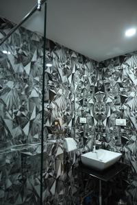 baño con lavabo y pared de azulejos en Hotel Trax International en Jamshedpur