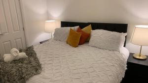 a white bed with pillows and a stuffed animal on it at Pristine 3-Bed House in Grays in West Thurrock