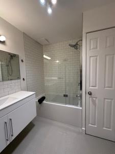 ein weißes Bad mit einer Badewanne und einer Dusche in der Unterkunft Le 315B Limoilou "parking inclus" in Québec