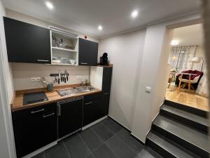 a small kitchen with black cabinets and a sink at Boarding House Alte Schusterei am Ahnepark in Vellmar