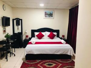 a bedroom with a large bed with red pillows at Miami Hotel Apartment in Sharjah