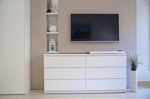 a white dresser with a tv on a wall at Appartamento Emozione Mare Blu San Terenzo in Lerici