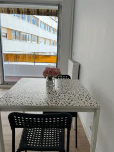 uma mesa com um vaso de flores com uma janela em Le Central - Studio avec terrasse Camas,Timone em Marselha