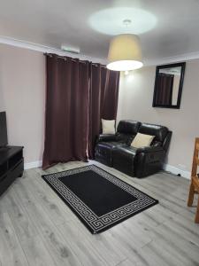 a living room with a black leather couch and a rug at Tuscawilla 2 in Plumstead