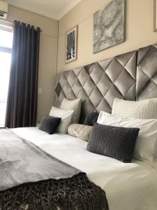 een slaapkamer met een groot bed met witte lakens en kussens bij Maerua Mall Luxe Accommodations 3rd Floor in Windhoek
