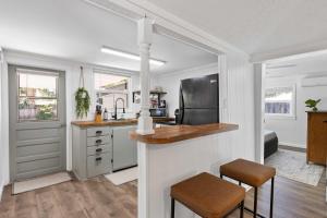 a kitchen with white cabinets and a counter with stools at 4 Mi to Dtwn Jensen Beach Cottage in Jensen Beach