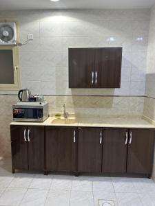 eine Küche mit einer Spüle und einer Mikrowelle in der Unterkunft شقة مفروشة غرفتين بدخول ذاتي in Al Kharj
