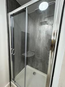 La salle de bains est pourvue d'une douche avec une porte en verre. dans l'établissement VicVic Guest house, à Oldham