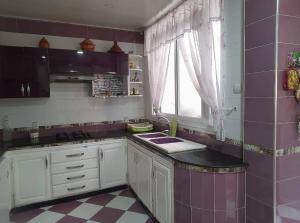 eine Küche mit einer Spüle und einer lila Kachelwand in der Unterkunft Appartement à Oran in Oran
