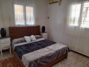 ein Schlafzimmer mit einem großen Bett und zwei Fenstern in der Unterkunft Appartement à Oran in Oran