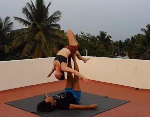 Eine Frau ist auf einem Mann, der Yoga macht. in der Unterkunft Palace Hostel by Borrbo in Mysore