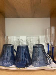 three blue vases sitting on a shelf with glasses at Новые апартаменты рядом с EXPO in Taldykolʼ