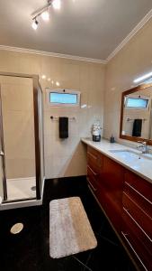 a bathroom with a shower and a sink and a mirror at Residência do Saramago in São Vicente