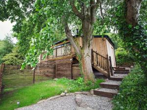 eine Holzhütte mit einem Baum neben einem Zaun in der Unterkunft 1 bed property in Gilwern Brecon Beacons 75206 in Gilwern