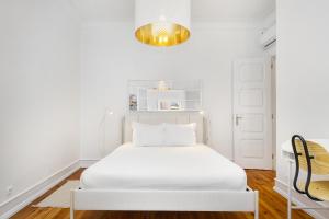biała sypialnia z białym łóżkiem i żyrandolem w obiekcie WHome Mid-Term Marvel: Your Home Away from Home w Lizbonie