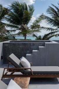 a lounge chair on a patio with palm trees in the background at Umi Tulum in Tulum