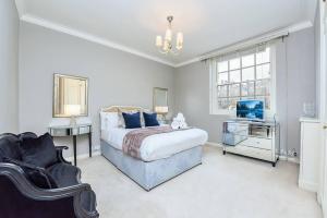 a bedroom with a bed and a tv and a chair at 2 Bedroom Apartment- Mayfair (4) in London